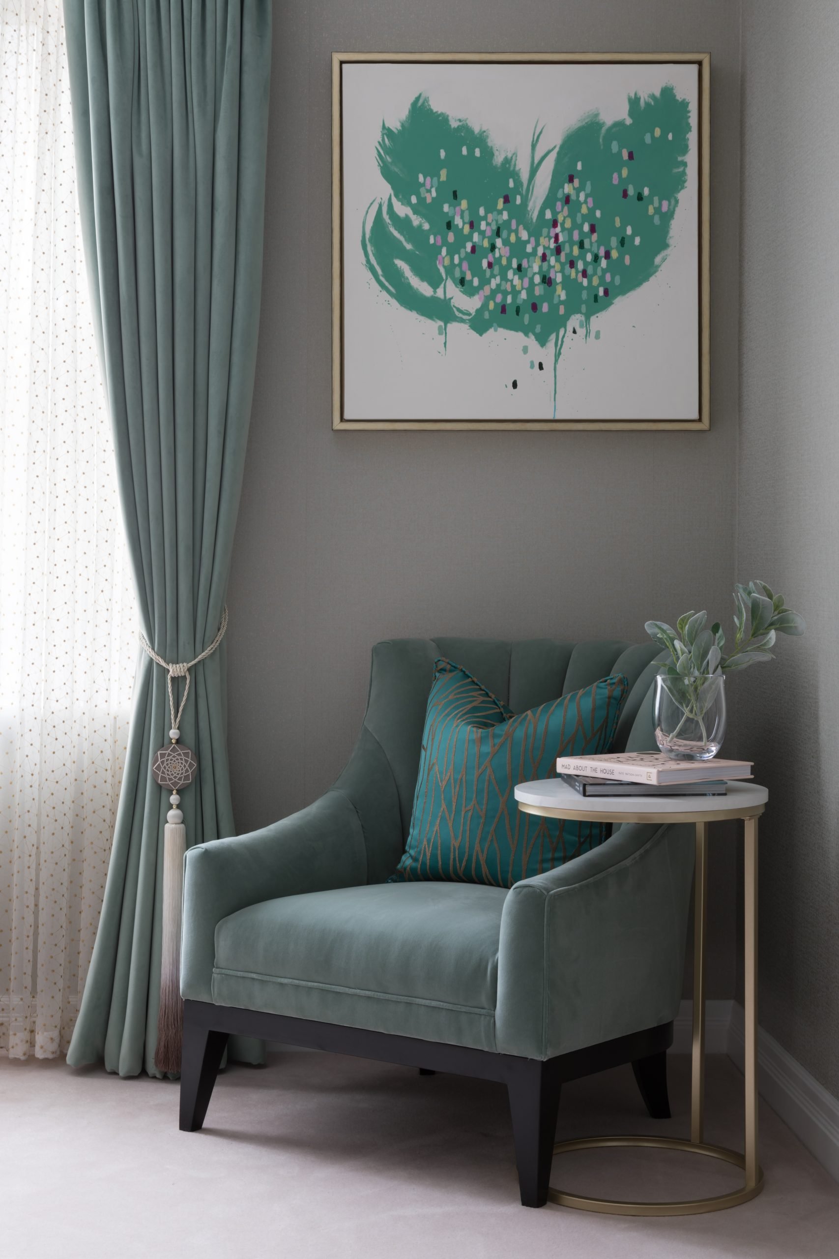 Sage coloured armchair with geometric side table and green and white art piece to wall