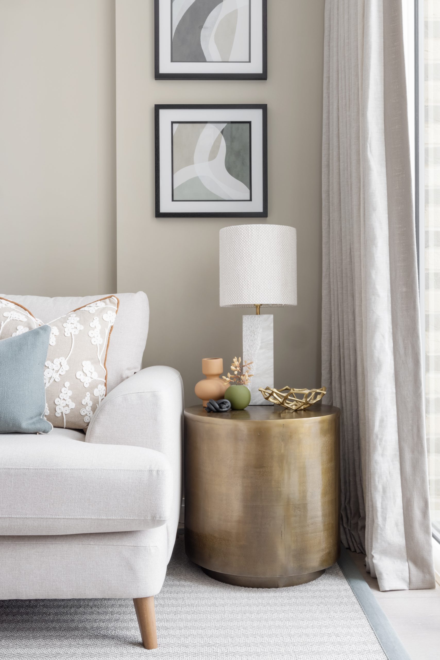 Bronze/brass effect side table with marble effect lamp with fabric white lampshade and artwork above.