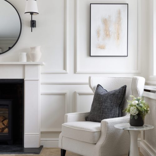Modern living room with white painted walls and white corner armchair and charcoal coloured cushion to chair
